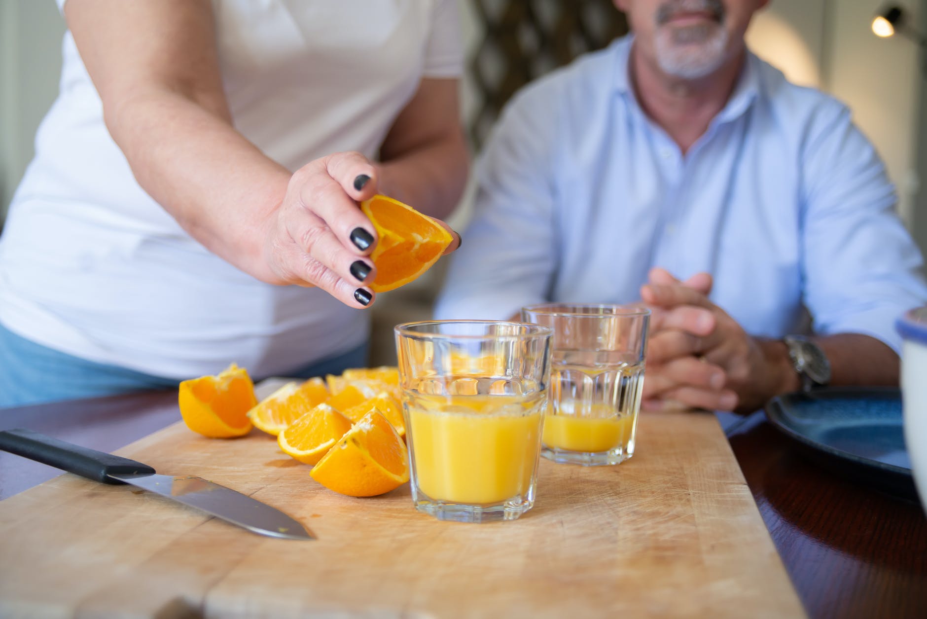 person making orange juice on a wooden chopping board