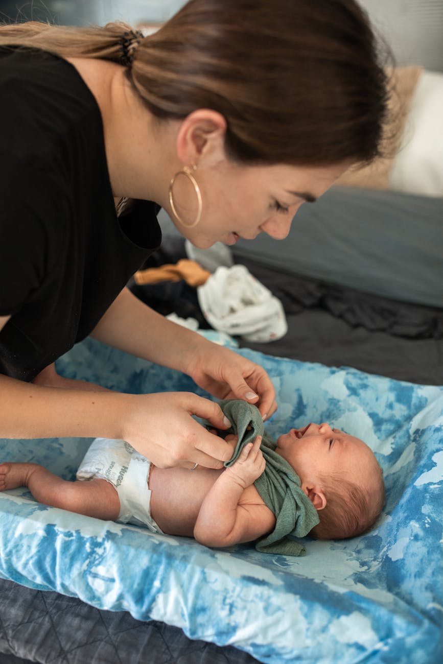 woman putting clothes on her baby