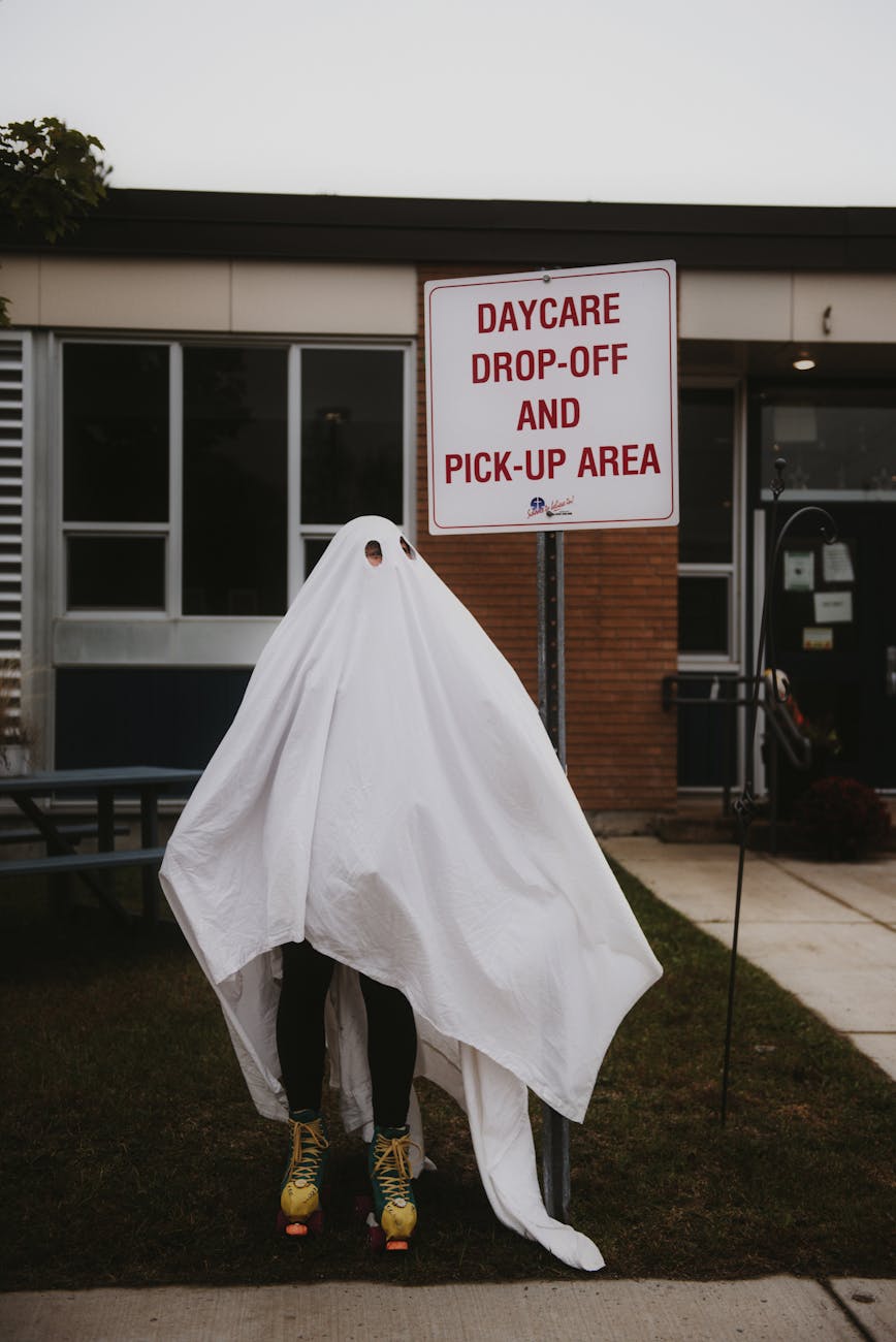 person in ghost costume standing in front of daycare sign